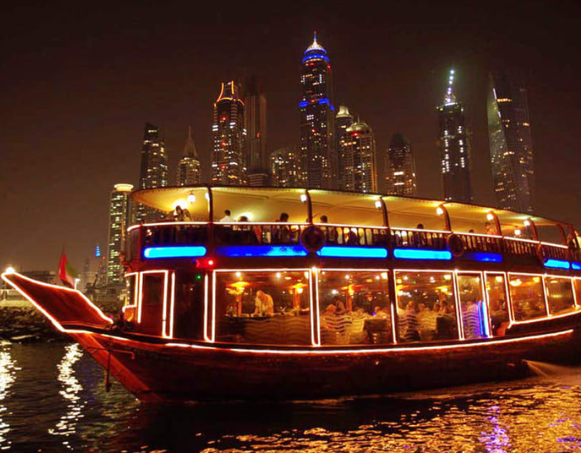Dubai Creek dhow cruise with traditional wooden boat, Old Town skyline, and evening lights – cultural dinner cruise